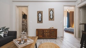 Ein modernes Wohnzimmer mit Holzboden, einem dunklen Sofa, einer Holzkommode und zwei Wandspiegeln.