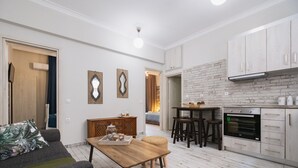 Eine moderne Küche mit weißen Schränken, einer Zierleiste aus Ziegelsteinen und einem Essbereich mit einem Holztisch und Stühlen.