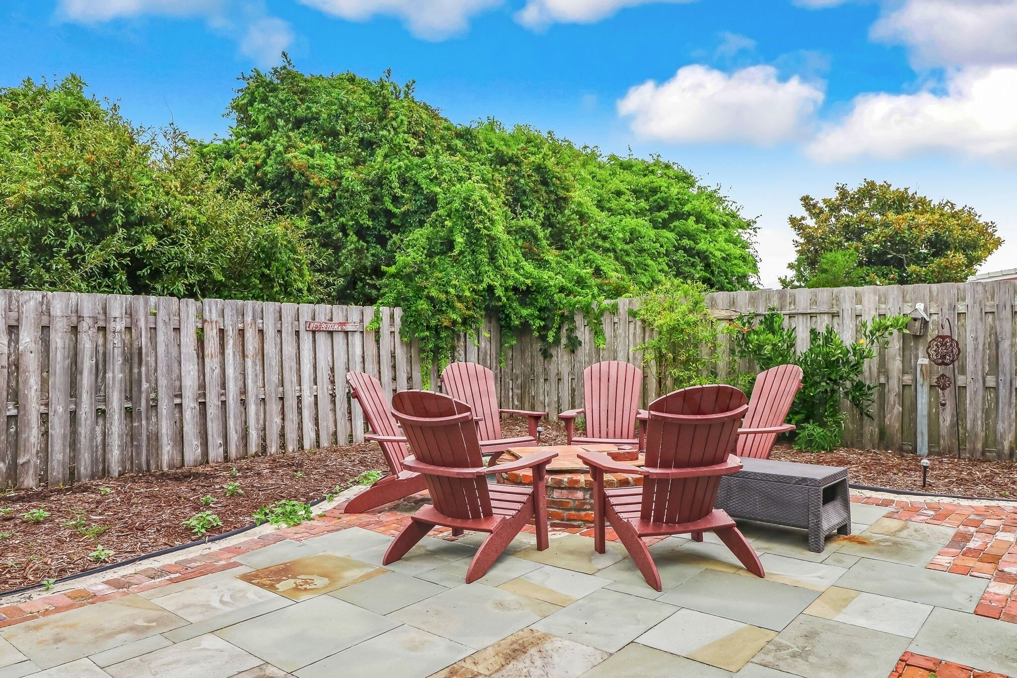 A patio with Adirondack chairs and a fire pit.