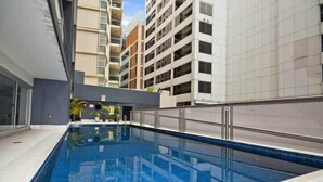 A swimming pool with a tiled edge, surrounded by modern buildings with balconies. - A Modern & Stylish Studio Next to Darling Harbour (Sydney)
