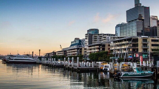 A waterfront cityscape with modern buildings, a marina with boats, and a docked ferry. - A Modern & Stylish Studio Next to Darling Harbour (Sydney)