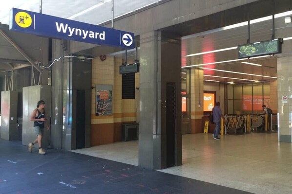 A train station platform with a sign for 'Wynyard' and an escalator.
