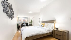 A bedroom with a wooden bed, a nightstand, and a desk with a chair. - A Modern & Stylish Studio Next to Darling Harbour (Sydney)