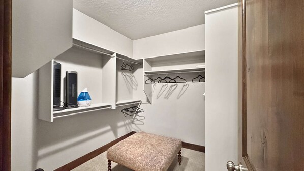 Une petite pièce bien éclairée, avec un banc, un miroir et une étagère sur laquelle se trouvent un radiateur et un vaporisateur.
