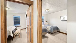 Een slaapkamer met een bed, een bankje, een raam en een bord aan de muur.