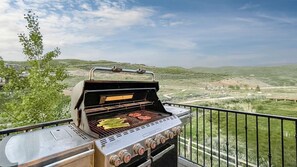 Een barbecue met meerdere branders en een heuvellandschap op de achtergrond.