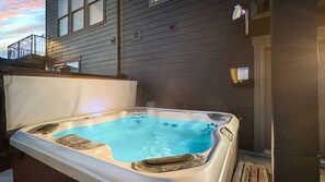 Een bubbelbad met een houten terras en een gebouw op de achtergrond.