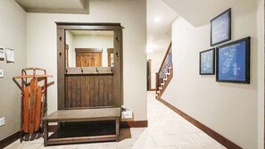Un couloir avec un banc en bois, un porte-manteau et des plans encadrés accrochés au mur.