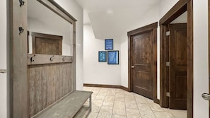Un couloir avec un banc en bois, une porte et des plans encadrés accrochés au mur.