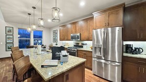 A modern kitchen with granite countertops, stainless steel appliances, wooden cabinets, and pendant lighting. - Fall Mountain Retreat•Hot Tub•BBQ•Community Amenities•Uinta Foothill Views (Heber City)