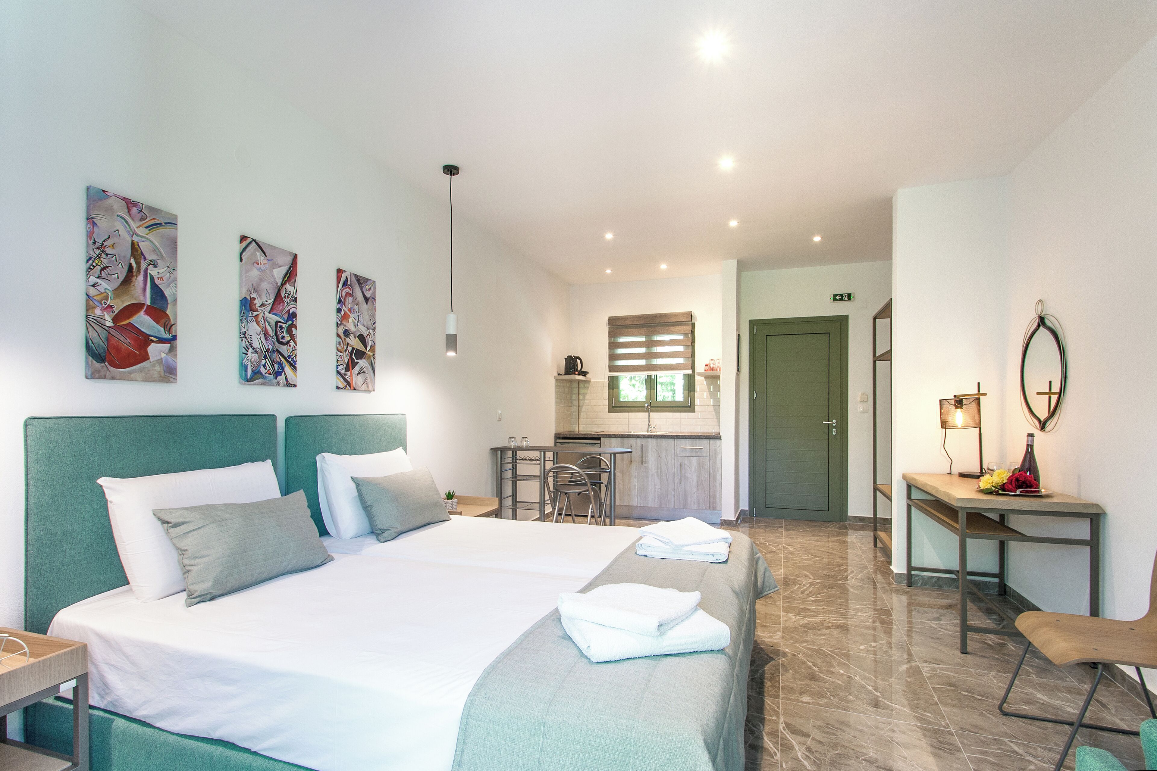 Camera d'albergo con due letti, una scrivania, una sedia e angolo cottura.