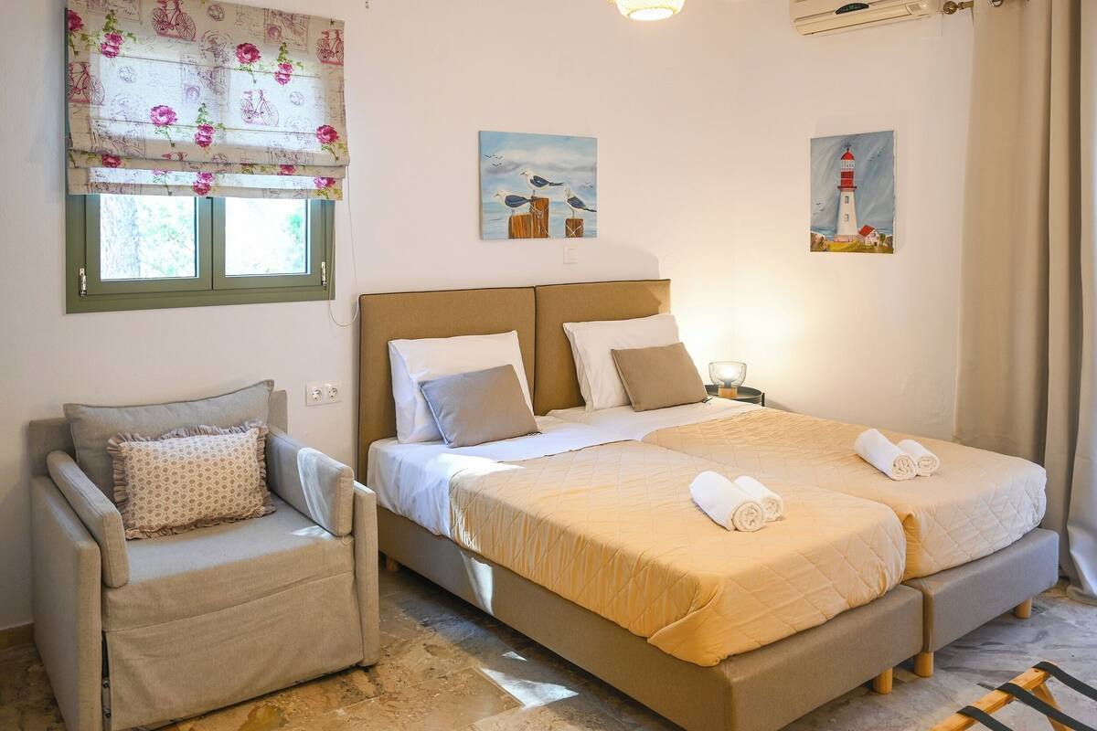 A bedroom with a bed, two bedside tables, a chair, and artwork on the walls.