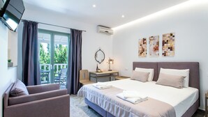Ein Hotelzimmer mit Bett, Schreibtisch, Sessel, Fernseher und Wandbildern.