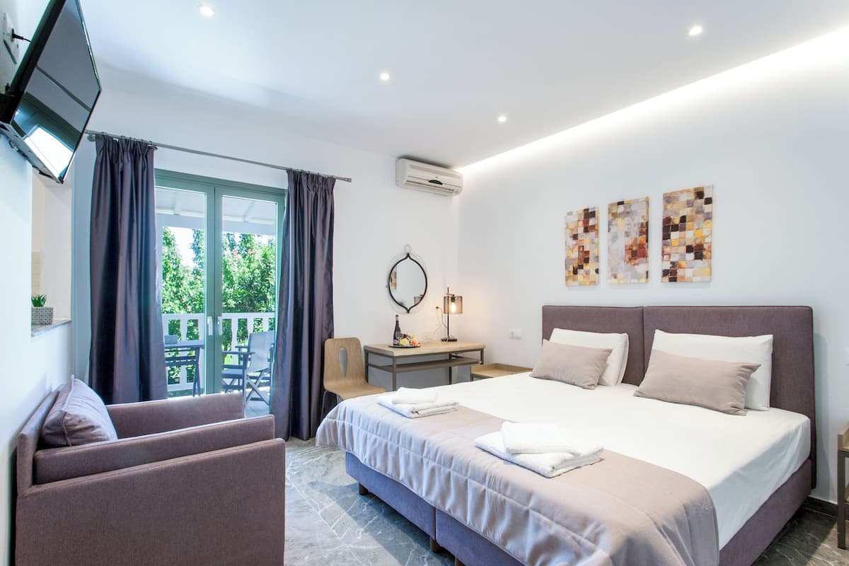 A hotel room with a bed, a desk, a chair, a TV, and artwork on the wall.