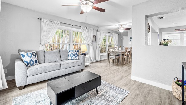 Un salon moderne avec un canapé gris, une table basse noire et un ventilateur de plafond.