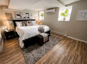 A bedroom with a bed, bedside tables, a rug, and a window. - Stylish Cool Springs Apt, King Bed (Wilmington)