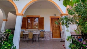 A courtyard with a table and chairs, a wooden door, and a blue umbrella. - Villa Sophia by CorfuEscapes (Corfu)