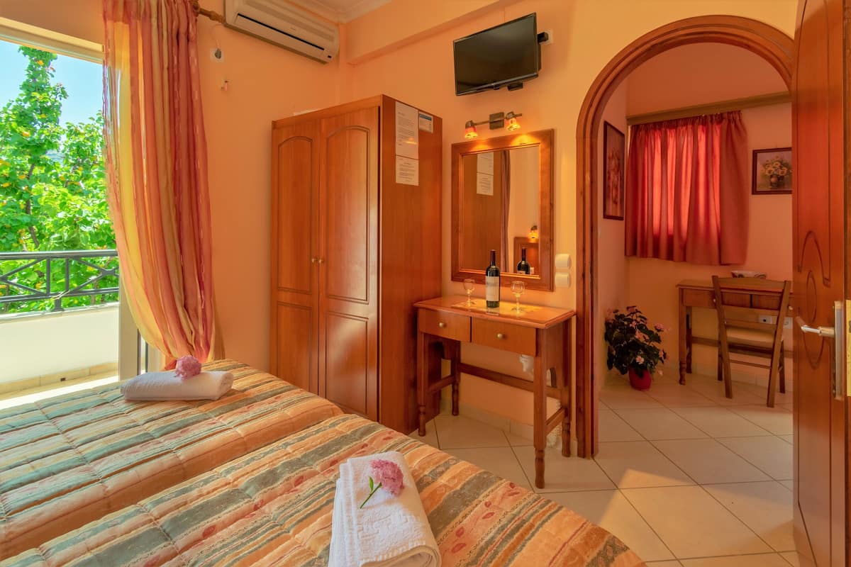 Ein Hotelzimmer mit einem Bett, einem Holztisch, einem Spiegel und einem durch einen Bogen sichtbaren Badezimmer.