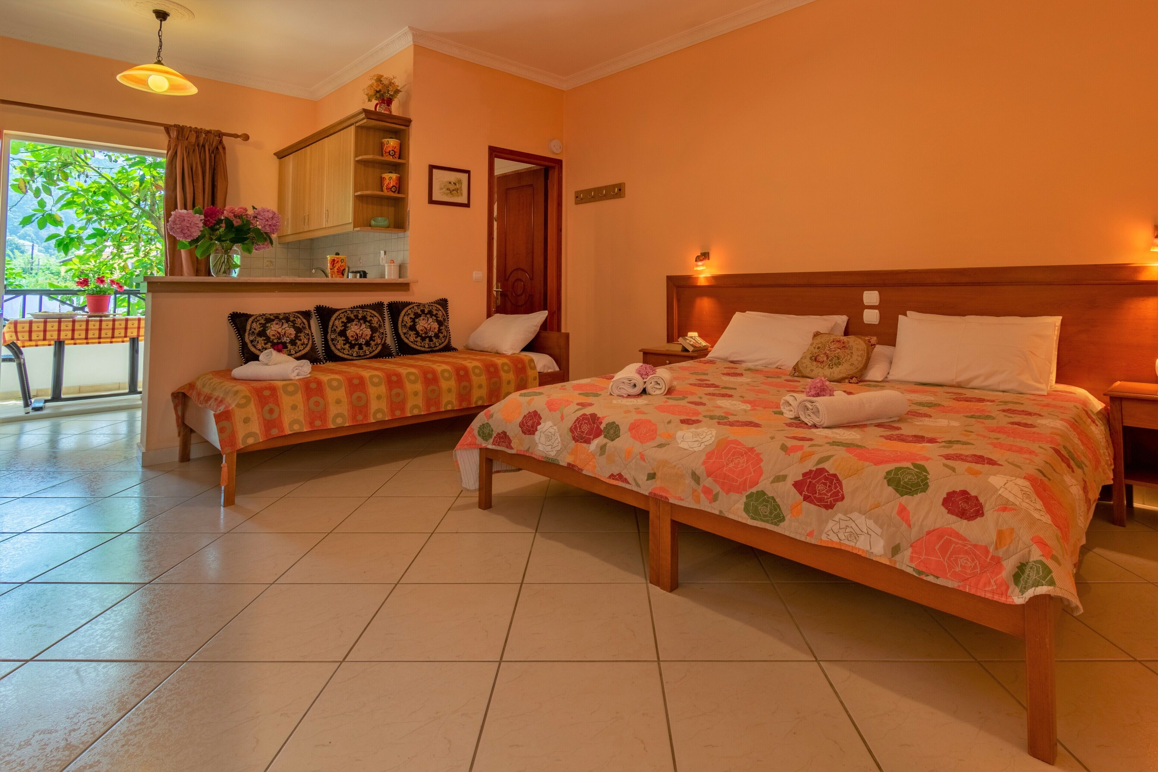 Une chambre d’hôtel avec deux lits, un balcon avec une table et un coin cuisine.
