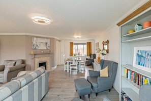 A living room with a fireplace, a dining area, and a bookshelf. - 3 Bed in Woolacombe (oc-dreams) (Woolacombe)