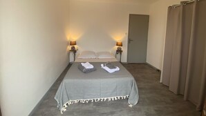 A narrow hotel room with a bed, two bedside lamps, a door, and a curtain. - Old mill in the Luberon (Mérindol)