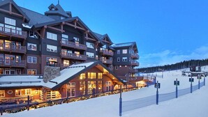 Un chalet à plusieurs étages doté de balcons, d'un télésiège et d'une pente enneigée.