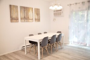 Ein Essbereich mit einem weißen Tisch, grauen Stühlen, einer Kristallleuchter und drei Bildern an der Wand.