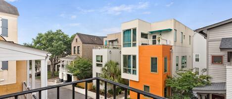 Un barrio residencial con edificios modernos, cielo despejado y una calle con barandilla.