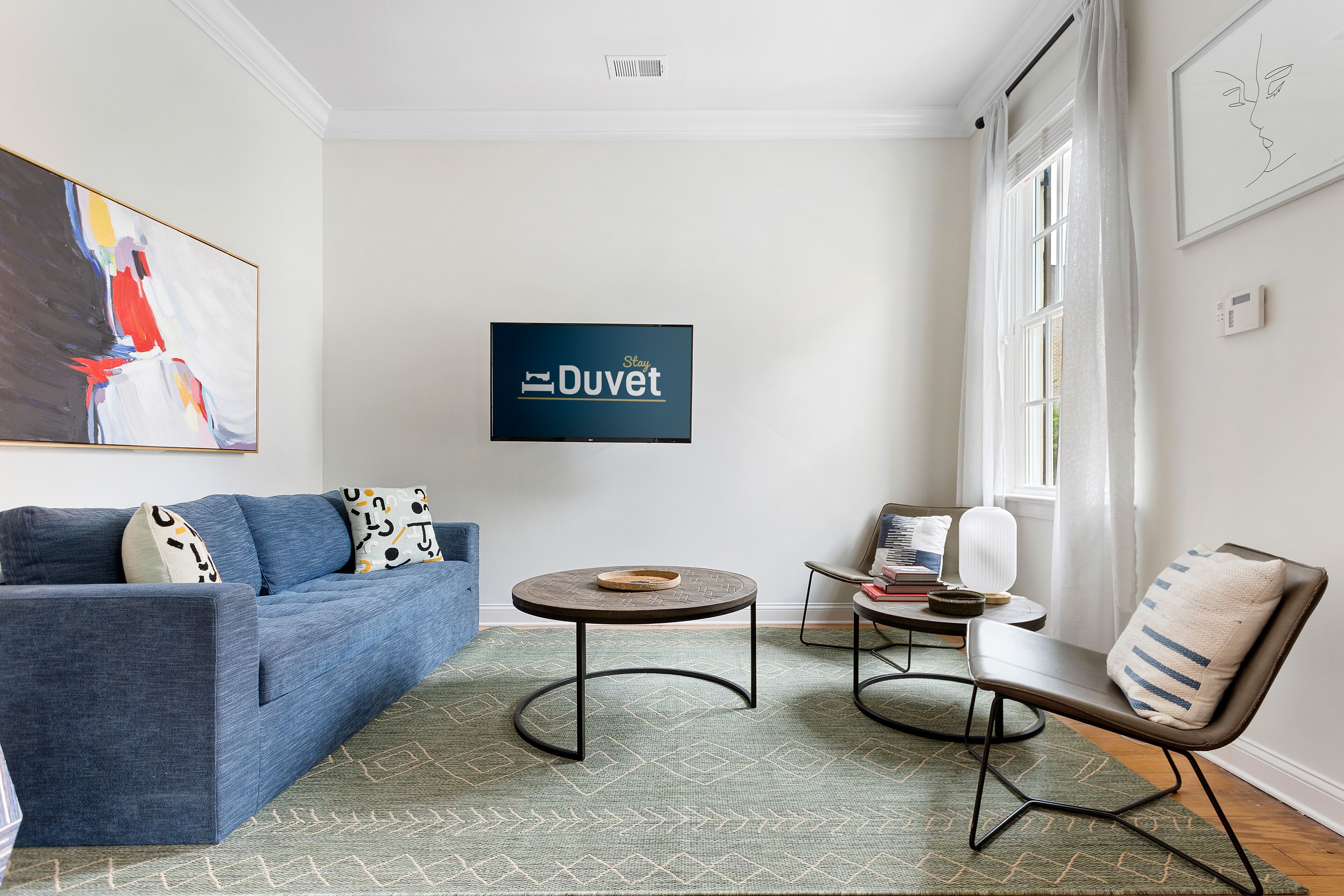 A modern living room with a blue sofa, a round coffee table, and a side table with books.