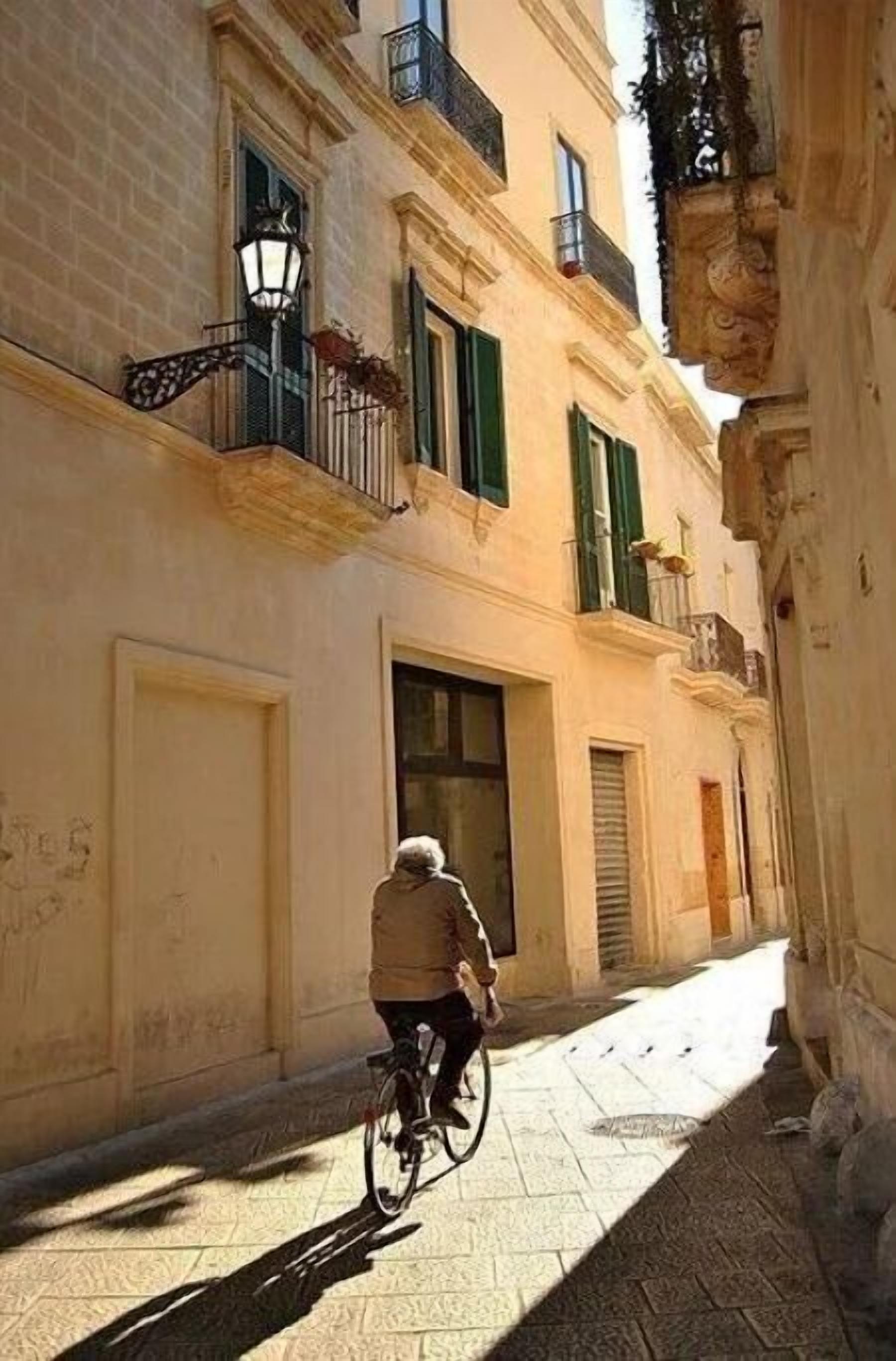 A narrow street with a person riding a bicycle.