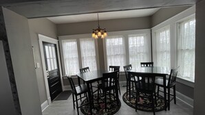 A dining room with a round table, six chairs, a chandelier, and large windows with sheer curtains. - Lg Historic.  2 bulk MSU. Hammond.  OTC.  Downtown close (Springfield)