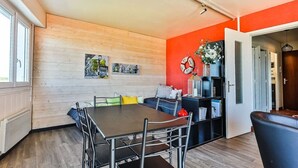 Ein moderner Essbereich mit einer Holzwand, einer roten Akzentwand und einem schwarzen Bücherregal mit Dekoration.