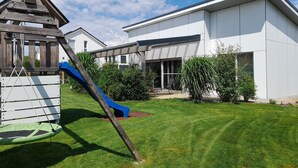 A modern building with a flat roof, a play structure with a slide, and a well-maintained lawn. - Bungalow on the Ostalb<br> (Eschach)