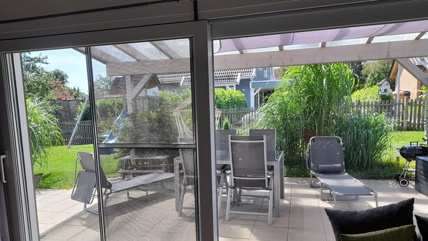 A patio with a glass door leading to a backyard. - Bungalow on the Ostalb<br> (Eschach)