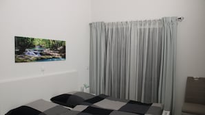 A bedroom with a bed, a chair, a picture on the wall, and a window with curtains. - Bungalow on the Ostalb<br> (Eschach)