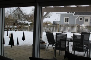 Een terras met een tafel en stoelen, een wit hekwerk en een huis op de achtergrond.