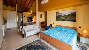 A bedroom with a wooden bed, a sofa, a desk, and a view of a landscape through a window. - Feeling House (Salò)
