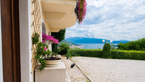 A balcony with potted plants and a view of a lake and mountains. - Feeling House (Salò)
