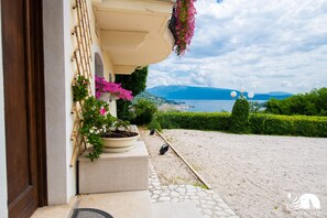 A balcony with potted plants and a view of a lake and mountains.
