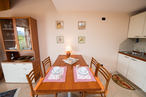 A dining table with chairs, a lamp, and a kitchen area with cabinets and a sink.