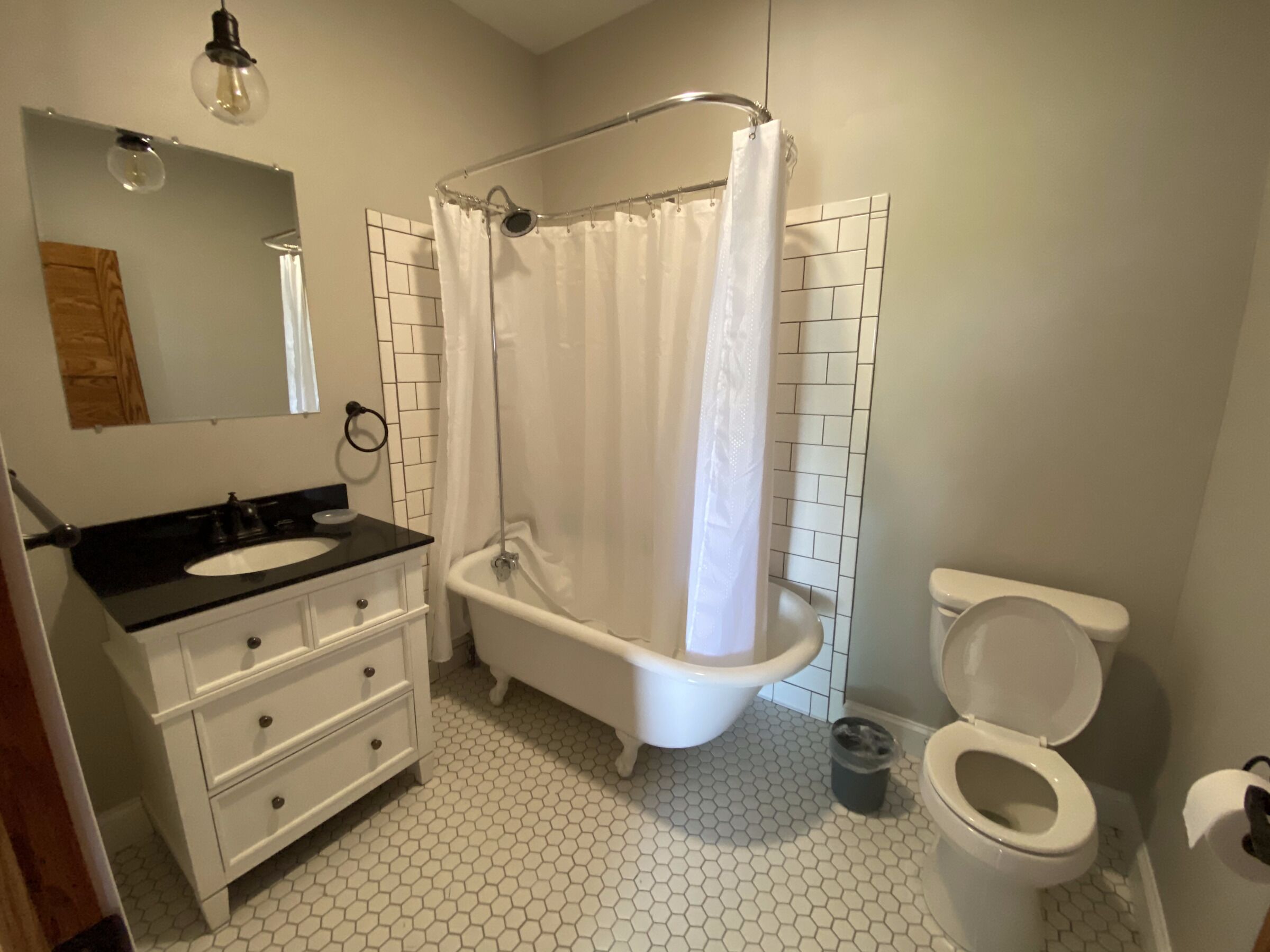A bathroom with a white bathtub, a white toilet, and a white sink with a black countertop.