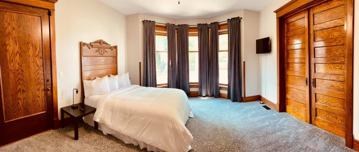 Un dormitorio con una cama grande, un armario de madera y un televisor en la pared.