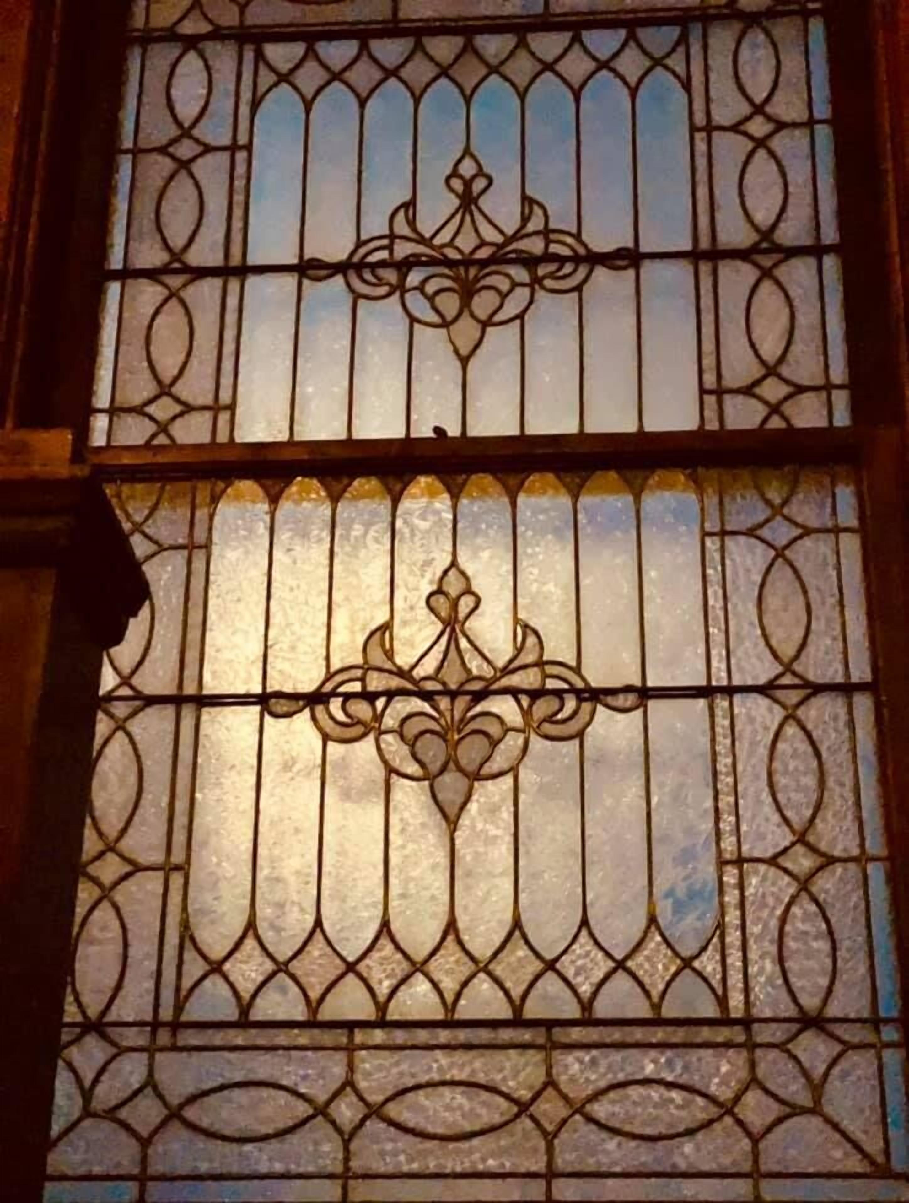A stained glass window with intricate metalwork and a central decorative motif.
