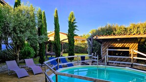 Une terrasse en bois avec une piscine, des chaises longues et une pergola en bois.