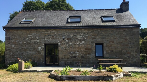 A stone building with a sloped roof, two windows, and a door. - Maison en Granit Typique Rénovée (Plounévez-Moëdec)