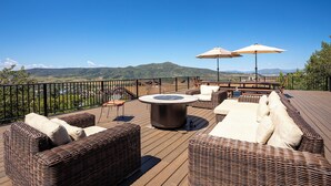 A deck with wicker furniture, outdoor seating, and umbrellas. - 90ST1 | Dog Friendly | Private Hot Tub | Short Walk to Slopes | Winter Shuttle (Steamboat Springs)