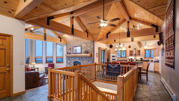 A spacious living area with a wooden ceiling, stone fireplace, and large windows. - 90ST1 | Dog Friendly | Private Hot Tub | Short Walk to Slopes | Winter Shuttle (Steamboat Springs)
