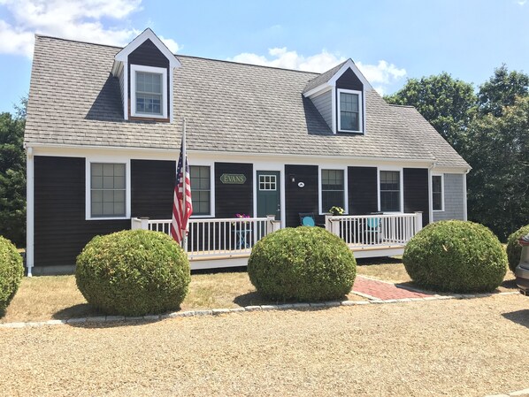 A two-story house with a dark exterior, a front porch with a railing, and a sign that reads "EVANS".