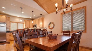 A dining area with a wooden table and chairs, a chandelier, and wooden cabinets.