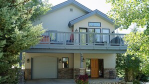 A two-story house with a balcony, a garage, and a stone foundation.